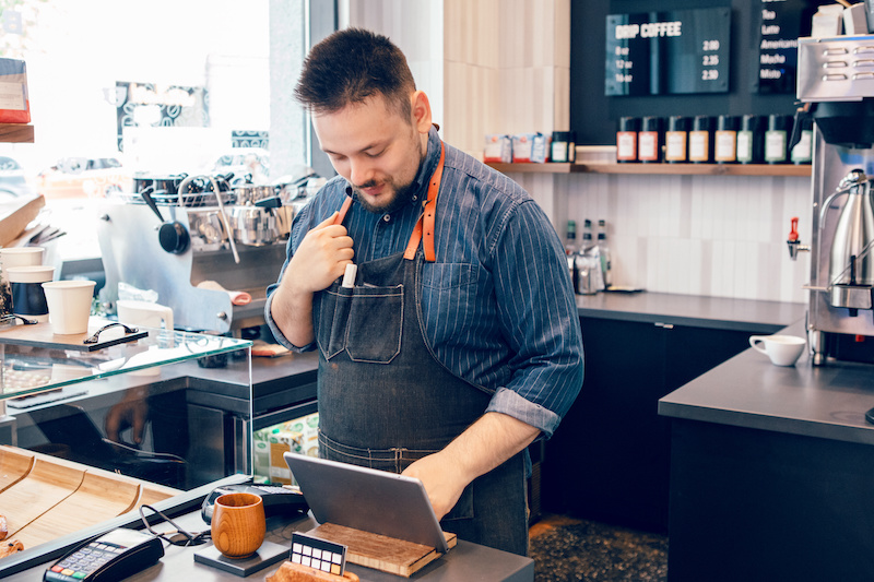 Young bearded man working at small business of coffee shop cafeteria.