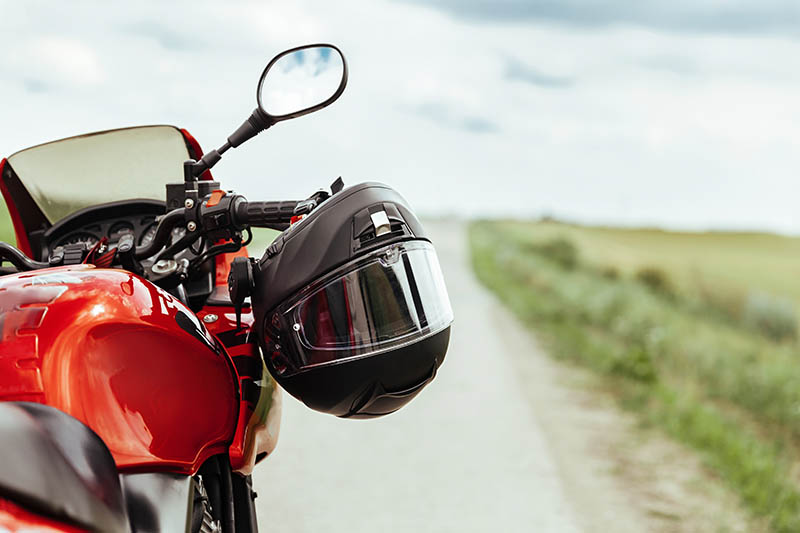 Black motorcycle helmet hanging on the handlebars of the motorcy Renters just moved into modern house, delivery service with boxes